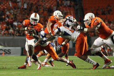 Sophomore Dallas Crawford (25) avoids the grasp of the Savannah State defenders during the game on Saturday night. The Canes won 77 to 7, and beat their record of most points scored during one game. Monica Herndon // Photo Editor 