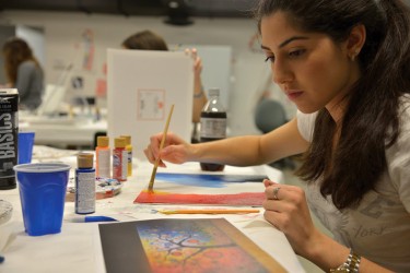 Junior Maria Ojeda looks at the pattern that inspired her painting during an Art for Kids meeting. During these meetings, students create different types of art that will eventually be auctioned off with all of the proceeds going to the Miami Children's Hospital. Charlotte Cushing // Staff Photographer