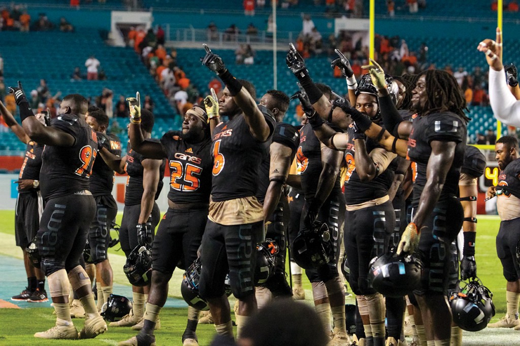 The football team sings the Alma Mater along with the crowd in light of the Hurricanes' 27-21 victory against the Caveliers Saturday evening at Sun Life Stadium. Hallee Meltzer // Photo Editor
