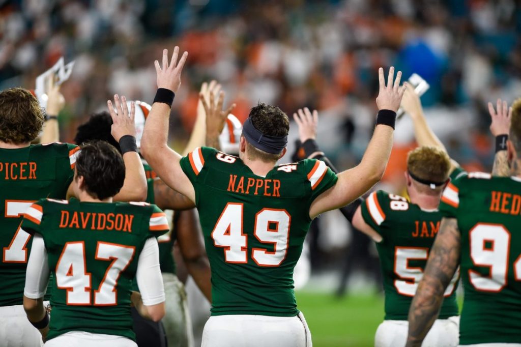 Then-freshman Long Snapper Mason Napper and other members of the canes football team hold up fours before the start of the fourth quarter on Nov. 9, 2019.