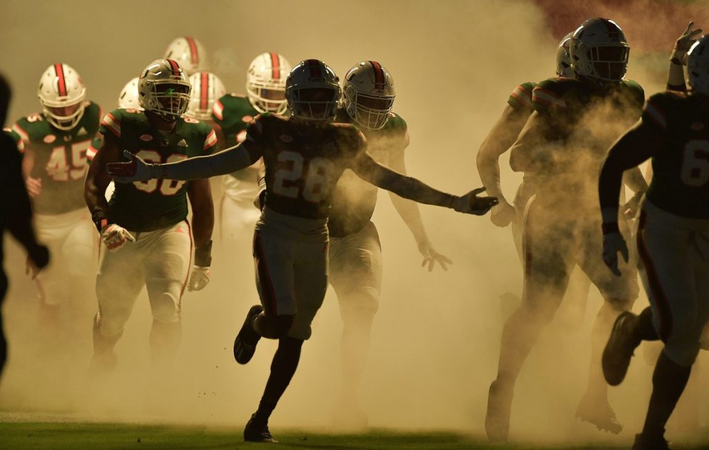 'Canes football players run on the field before playing Florida State at Hard Rock Stadium on Sept. 26.
