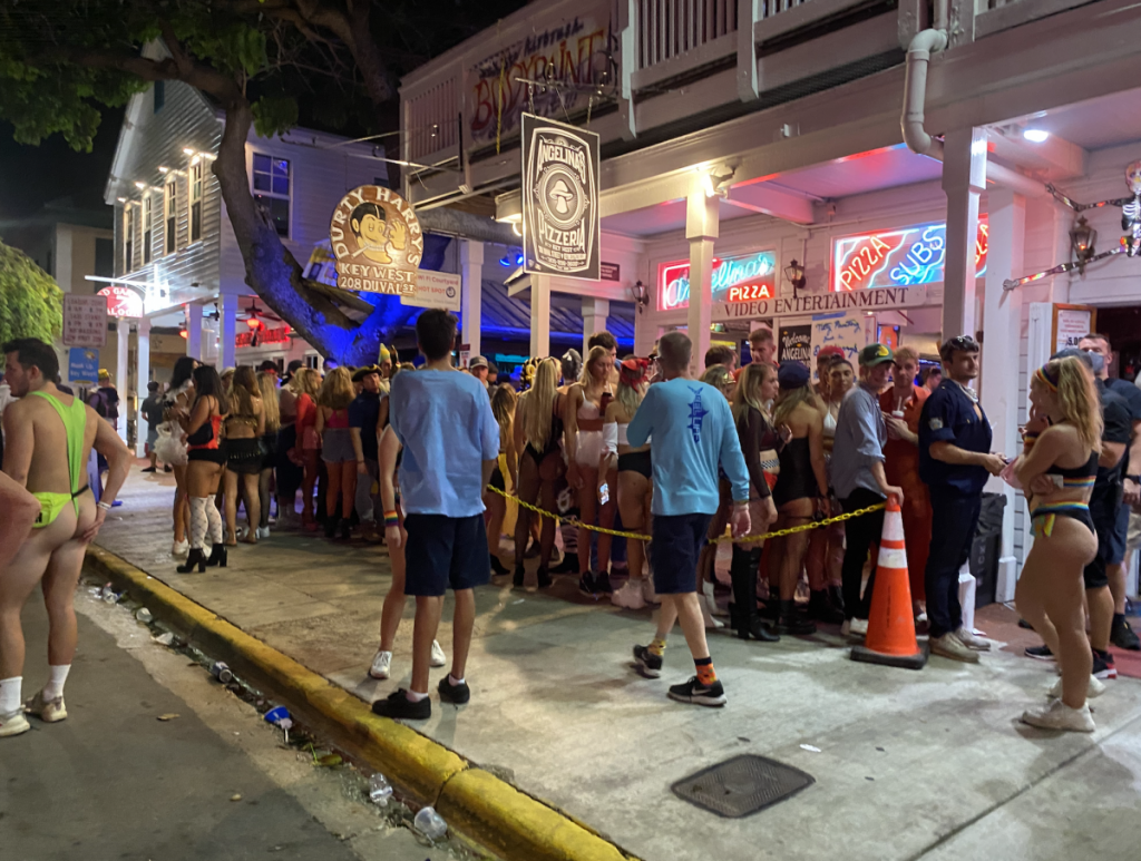 A large group of people, several identified as University of Miami students, wait in line outside Durty Harry's on Duval Street in Key West on Saturday, Oct. 31.