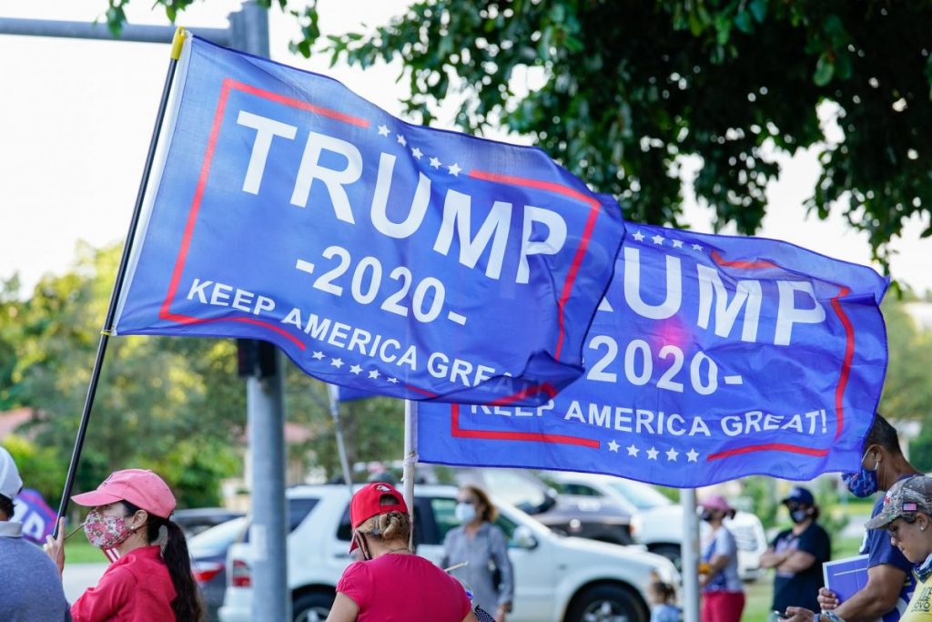 Trump Supporters fly Trump campaign flags in a show of support for the president at an intersection near Coral Gables Library on Tuesday, Nov. 3.