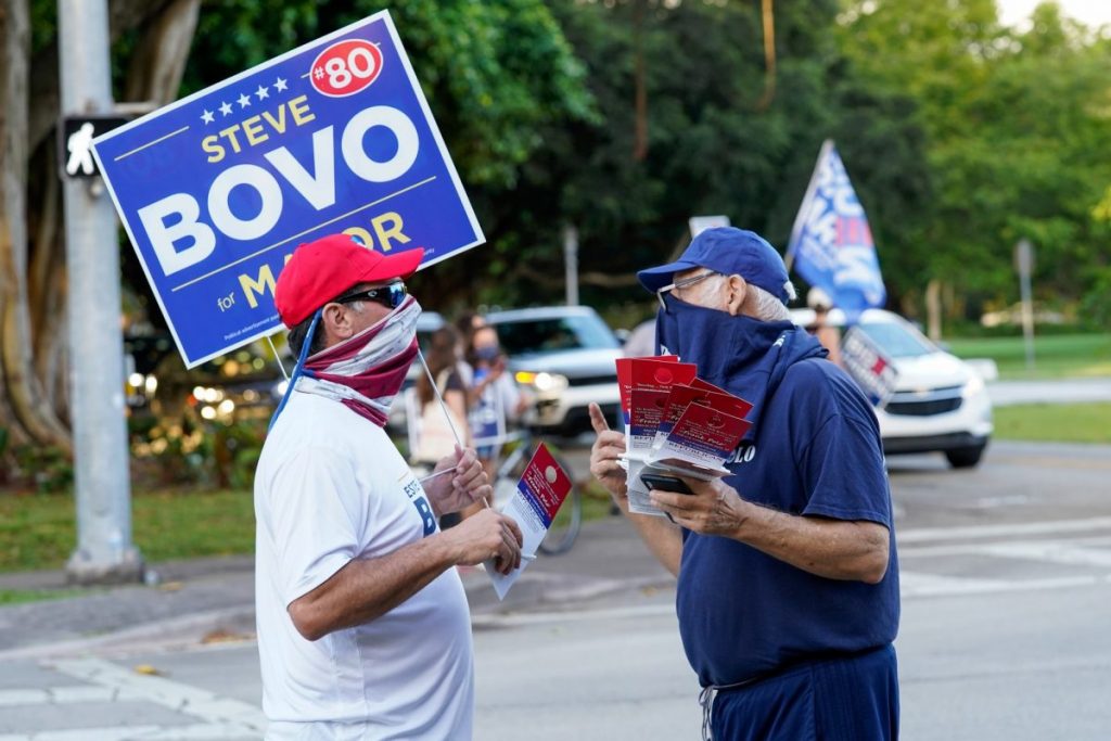 A Bovo supporter takes campaign literature from a supporter of Frank Polo, a republican write-in candidate seeking to represent Florida’s 27th congressional district, at an intersection near the Coral Gables Library on Tuesday, Nov. 3.