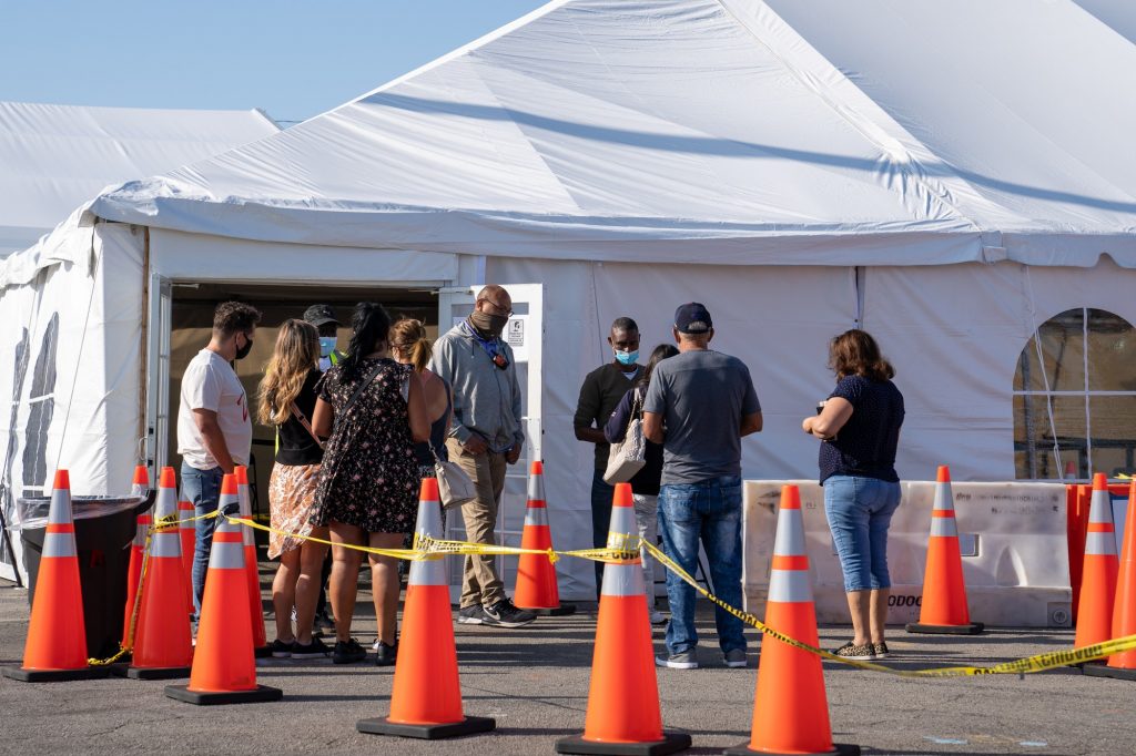 People seeking vaccination speak with site employees to confirm eligibility before being sent to the registration tent at the Federal Emergency Management Agency Miami Dade College North Campus vaccination site on March 21, 2021.
