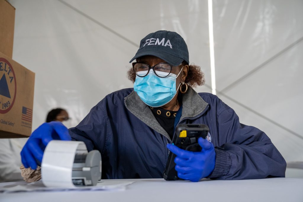 Faye York, a FEMA employee, waits to register people in the second registration tent at the FEMA Miami Dade College North Campus vaccination site on March 21, 2021.