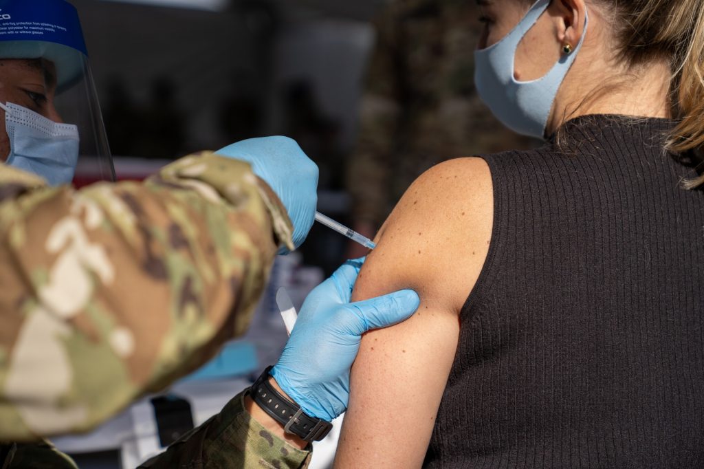 Federika Tovar receives a dose of the Pfizer-BioNTech Covid-19 vaccine from a member of the U.S. military at the FEMA Miami Dade College North Campus vaccination site on March 21, 2021.