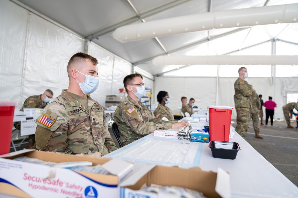 Members of the U.S. military wait to vaccinate Florida residents in the vaccination tent at the FEMA Miami Dade College North Campus vaccination site on March 21, 2021. 139 soldiers from Fort Riley, Kansas, were deployed to the site as a part of joint military assistance to state-run, federally supported community vaccination centers, according to a March 1 U.S. Army Public Affairs release.
