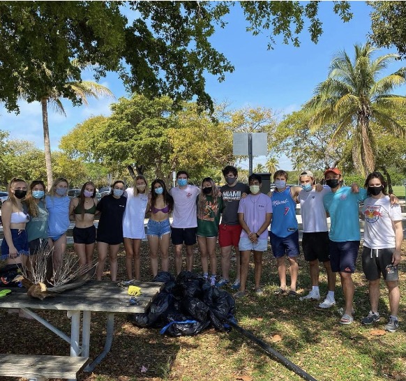 Esther Cai, middle with black mask and green shirt, poses with members of fraternity Lambda Chi Alpha and sorority Tri Delta after they collected more than 100 pounds of trash at a beach cleanup on March 20 at Crandon Beach. Photo Credit: Dawei Shao