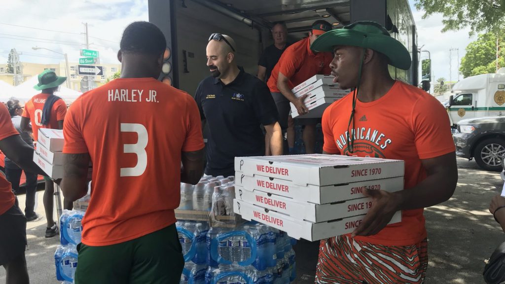 Kamren Kinchens (right) and Mike Harley Jr. (left), carry boxes of pizza out of a truck in Surfside, Fl.