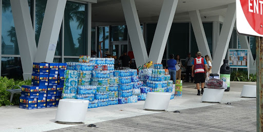 Water bottles and snacks line the entrance to the Town of Surfside Community Center on Saturday, June 27, as a Red Cross volunteer makes his way toward the building’s front door. The center was repurposed to support individuals impacted by the Thursday collapse of Champlain Towers South.