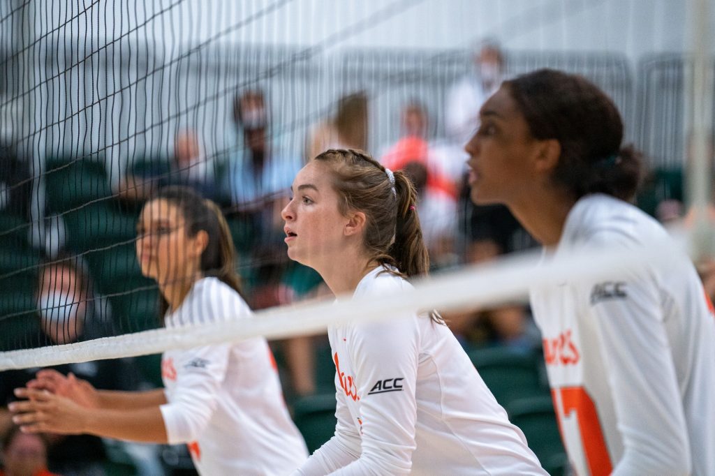Freshman middle blocker Ashley Carr and teammates prepare for the serve during the Canes’ game versus UMBC in the Knight Sports Complex on Aug. 29, 2021.
