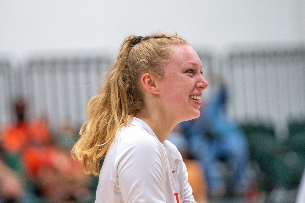 Junior setter Savannah Vach smiles and heads over to celebrate with teammates after the Canes scored a point during their match versus the University of Maryland, Baltimore College on Aug. 29, 2021.