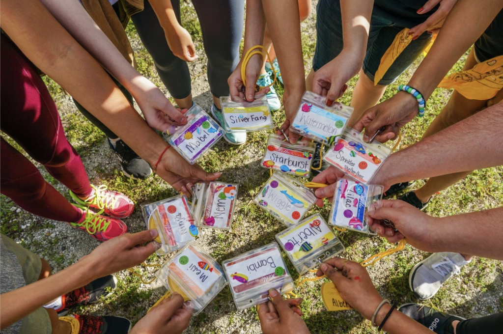 Camp Kesem participants huddle together to show name tags displaying their “Kesem names."