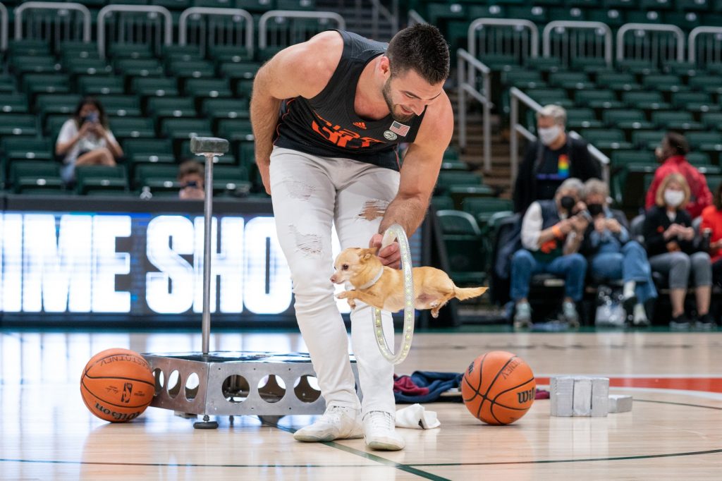 Christian Stoinev holds an illuminated hoop as “Scooby” jumps through during a halftime performance at Miami’s game versus Syracuse in The Watsco Center on Feb. 3, 2022.