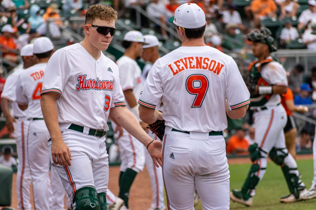 Freshmen Zach Levenson and JD Jones discuss outside Miami’s dugout in the Hurricanes’ 11-3 loss to Florida on Sunday, March 6, 2022 at Mark Light Field.