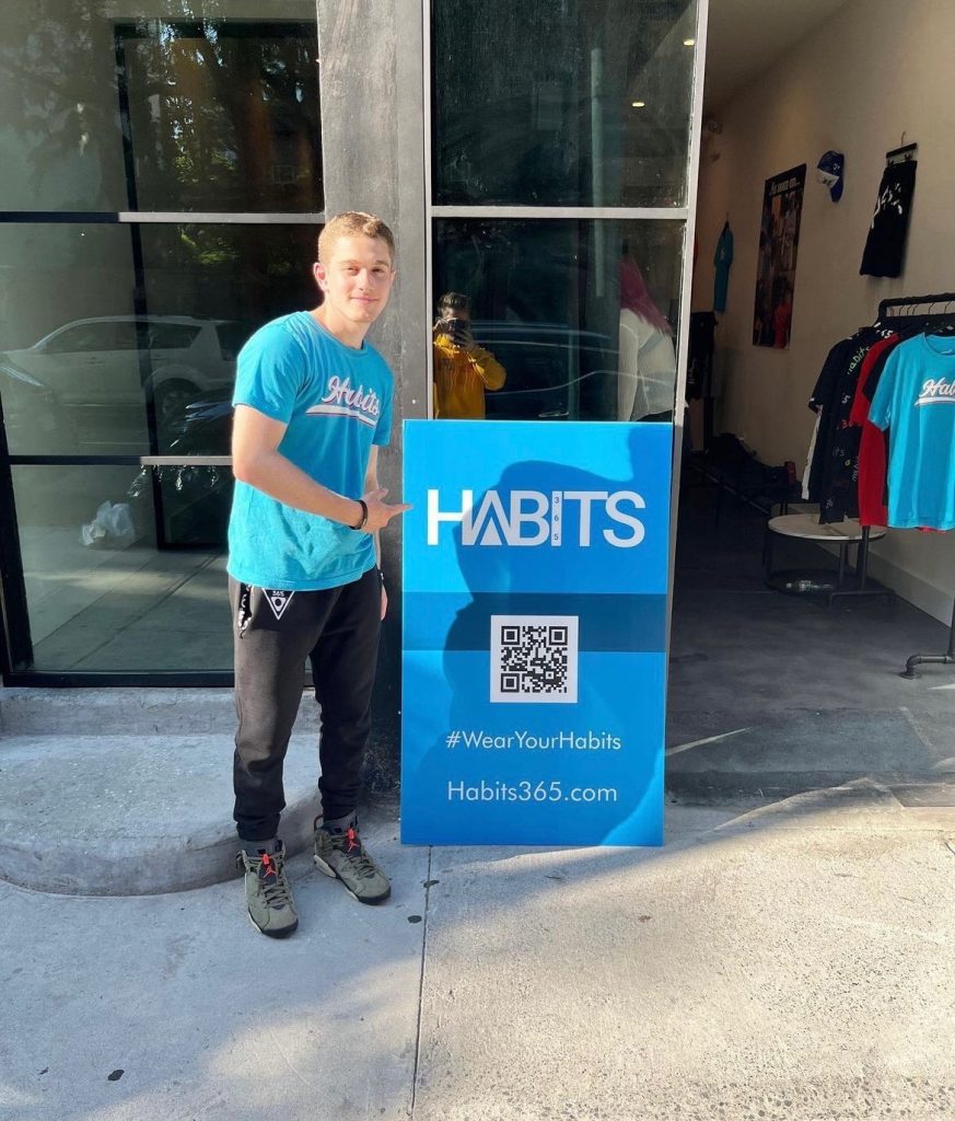 Eli Zied shows off Habits 365 website QR code outside of pop-up shop.