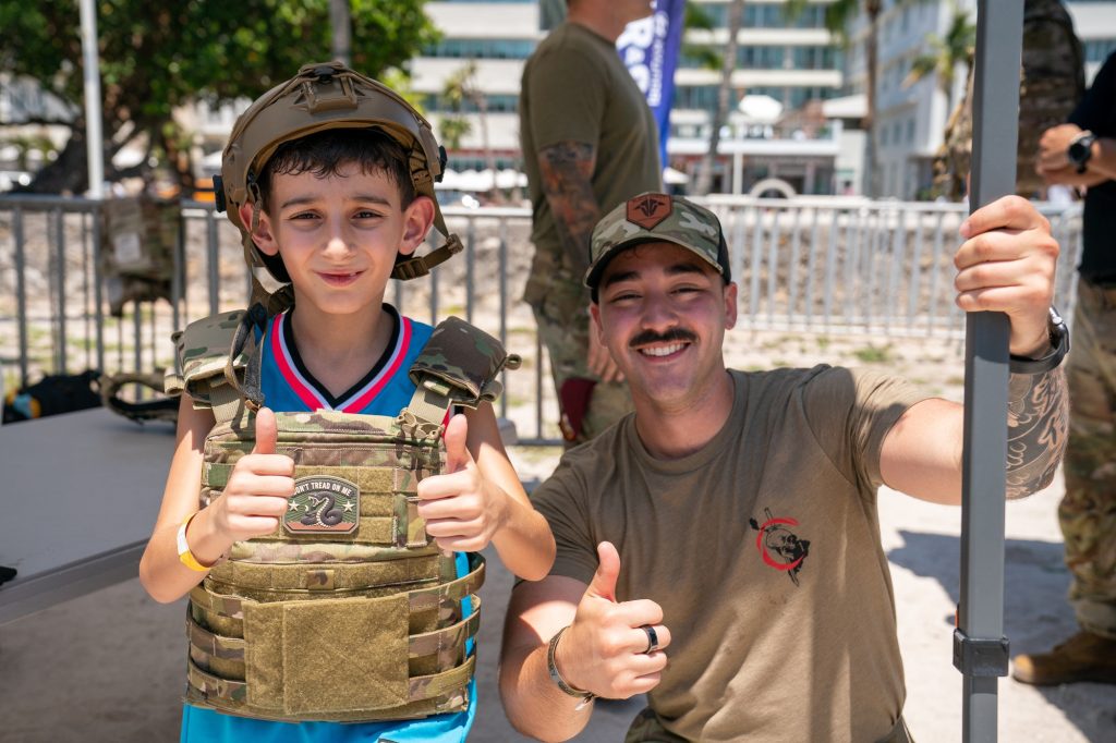 Federico, wearing a helmet and vest, poses with Sergeant Robles of the First Battalion, fourth Psychological Operations Group in the display village of the Hyundai Air and Sea Show at Miami Beach on May 28, 2023.