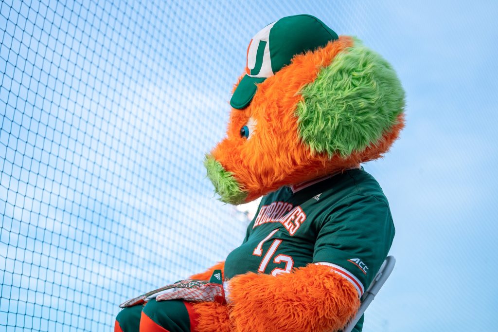The Miami Maniac watches warmups before the start of Miami’s Coral Gables Regional game versus the University of Maine at Mark Light Field on June 2, 2023.