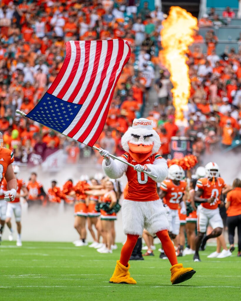 Sebastian the Ibis waves the American flag as ‘Canes football players take the field ahead of Miami’s game versus Texas A&M at Hard Rock Stadium on Sept. 9, 2023.