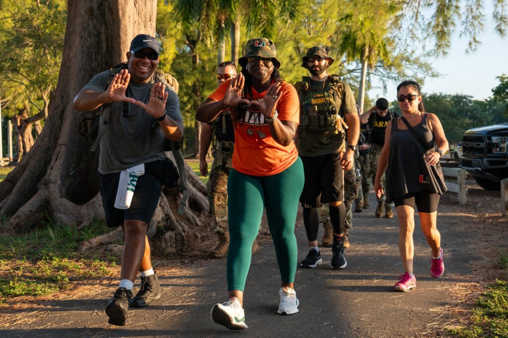 Members of UMPD throw up the U after completing a workout at the halfway point of the 9.11 mile memorial ruck at Tropical Park on Sept. 11, 2023.