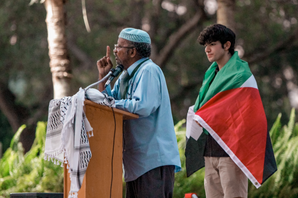 Senior Ramsey Shihadeh stands next to Imam Nasir Ahmad as he addresses the crowd at the vigil on Monday, Oct. 23.