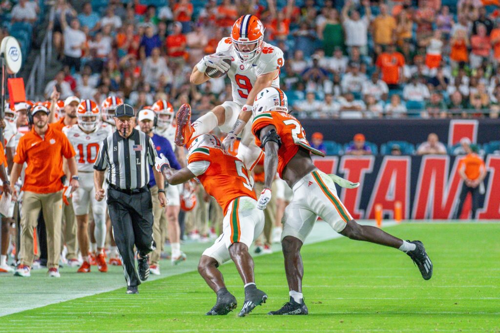 Clemson junior tight end Jake Briningstool attempts to hurdle safeties Kamren Kinchens and James Williams in the second quarter of Miami’s game versus Clemson at Hard Rock Stadium on Oct. 21, 2023.