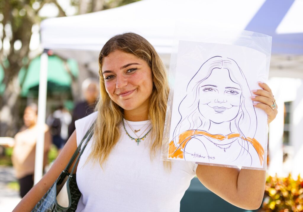 Junior marketing student Ellee Seitz poses with her caricature drawing at the 2023 Homecoming Opening Ceremony at Lakeside Patio on Oct. 23, 2023.