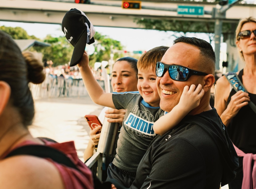 A father and son watch for family at the finish line of the Miami Marathon on Jan. 28, 2024.