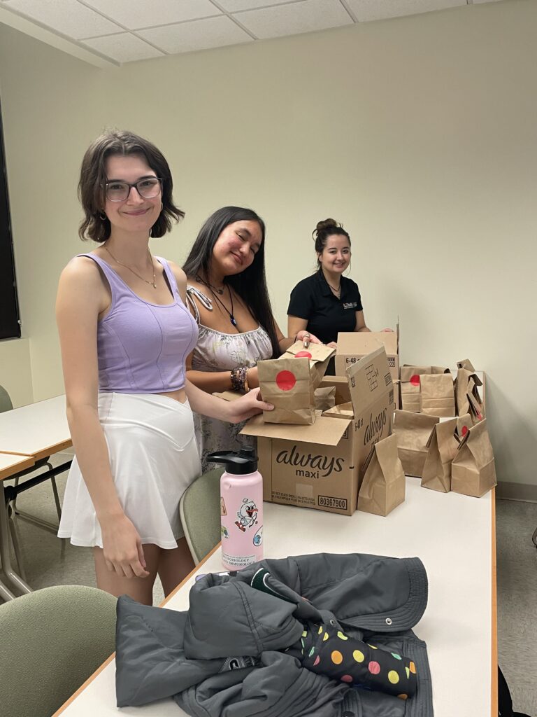 From left to right: Elena Thomson, Luna Plaza, and Sofia Del Mar Gomez Mahecha help pack menstrual care packages. Photo Credit: Lex Calderon